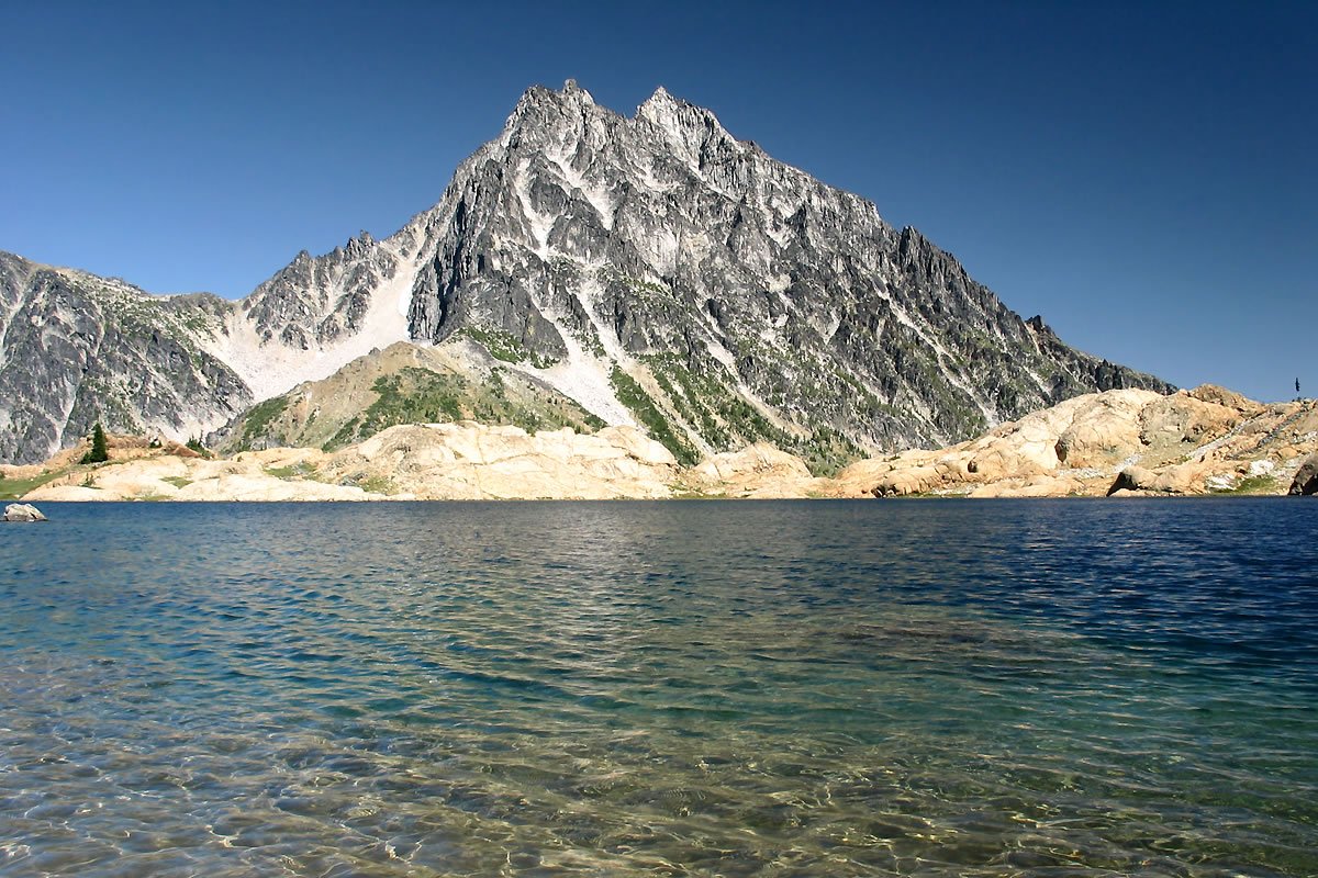 Ingalls Lake A tranquil mountain lake reflects the clear blue sky, bordered by rugged peaks and rocky shores.