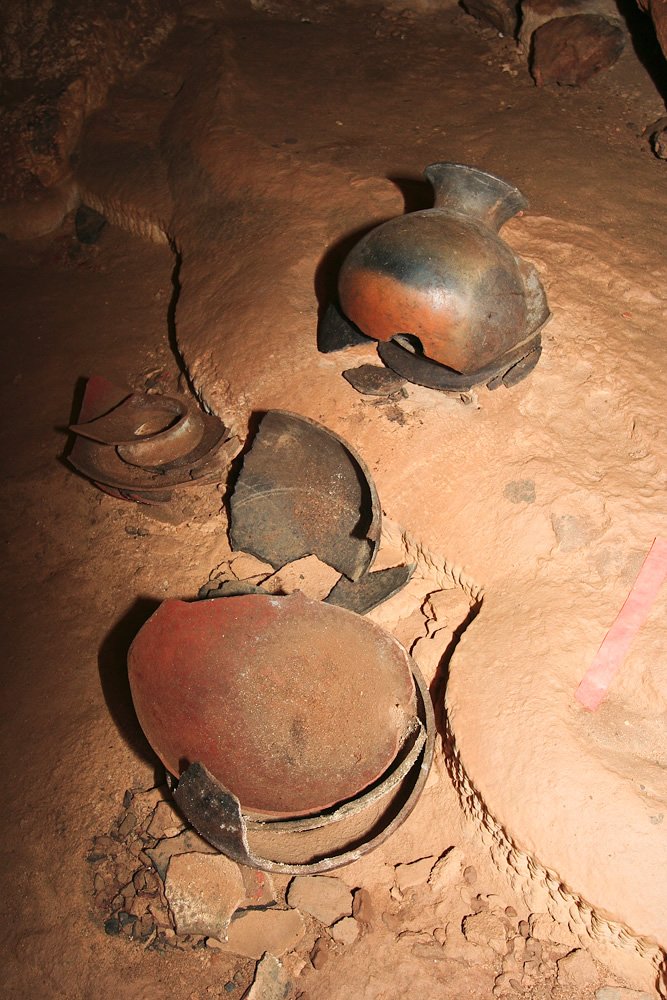 A collection of ancient pottery fragments displayed on a sandy surface.