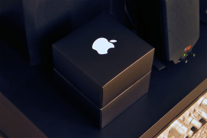 Discover the sleek design of an Apple product box in this close-up shot, highlighting the iconic logo illuminated against a dark background. This image captures the essence of modern technology mixed with simple elegance.