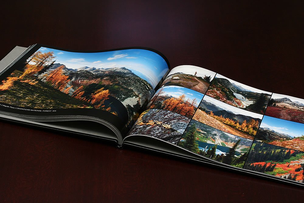 A photo book open to pages displaying vibrant autumn landscapes and mountain views.