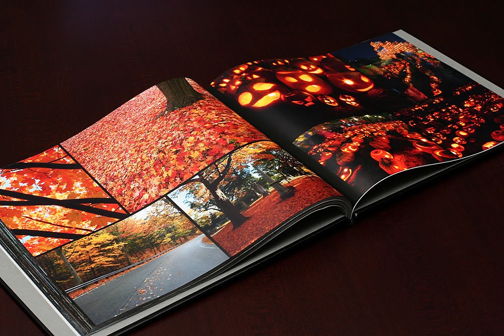 An open photo book showcasing vibrant autumn scenes. Red and orange fall foliage dominate the pages.