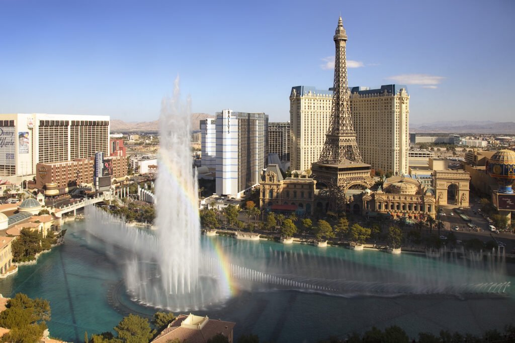 The iconic Bellagio hotel with the Eiffel Tower replica, surrounded by the famous dancing fountains creating a rainbow.