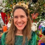 Woman wearing a flower crown at an outdoor market with festive decorations.
