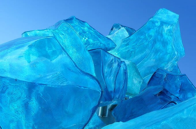 A stunning glass sculpture of vibrant blue ice-like structures against a solid blue backdrop.