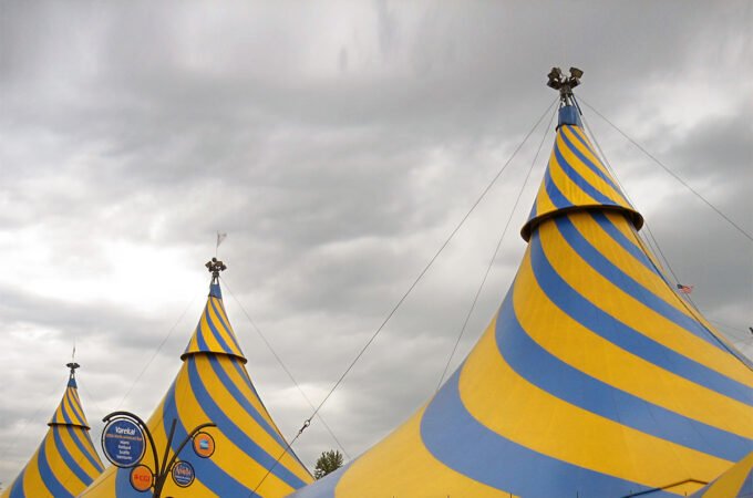 Yellow and blue striped circus tent top. Metal flag on top of the tent.