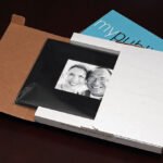 Christmas The image shows a couple from a personality photo, placed inside a brown paper bag alongside a white book and a blue booklet advertising 'mypub', captured from a top-down perspective. This arrangement suggests a cozy review or story-telling setting.