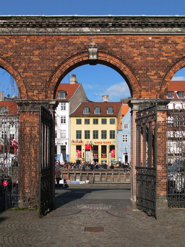 A brick archway frames a picturesque scene of European architecture