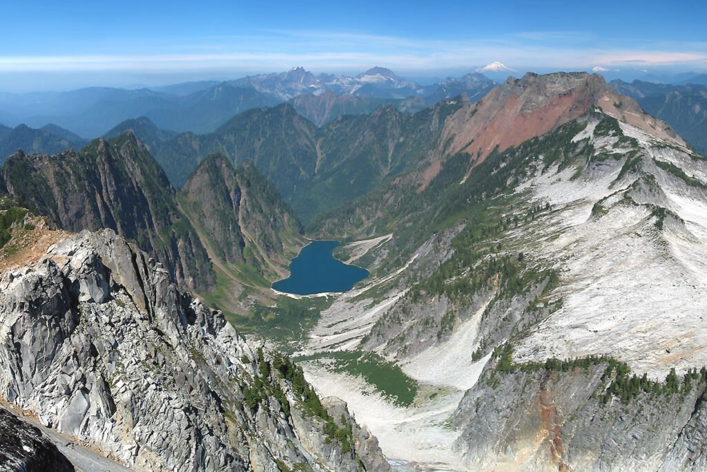 A breathtaking view of rugged mountain peaks with a serene alpine lake nestled below.