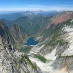A breathtaking view of rugged mountain peaks with a serene alpine lake nestled below.