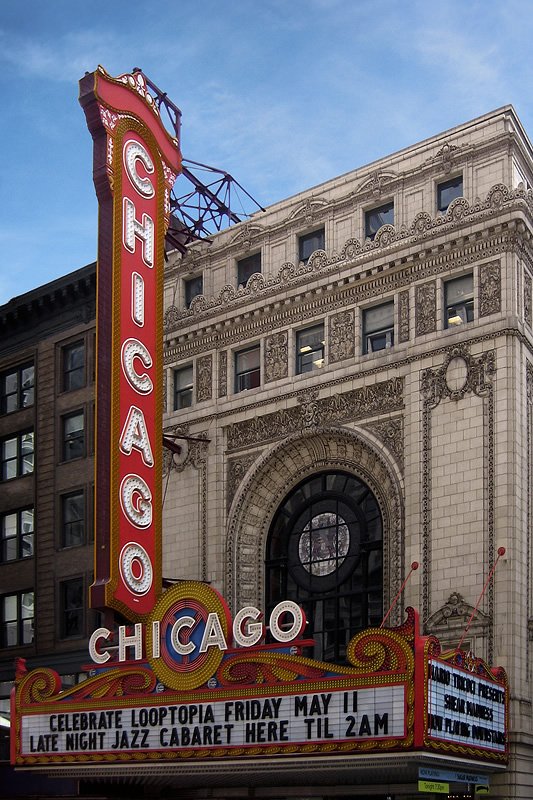 The iconic red neon Chicago Theatre sign stands tall against a clear blue sky, showcasing classic architectural beauty.