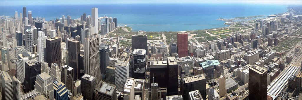 An aerial photograph showcasing the dense urban sprawl of Chicago's skyline and its surrounding suburbs.