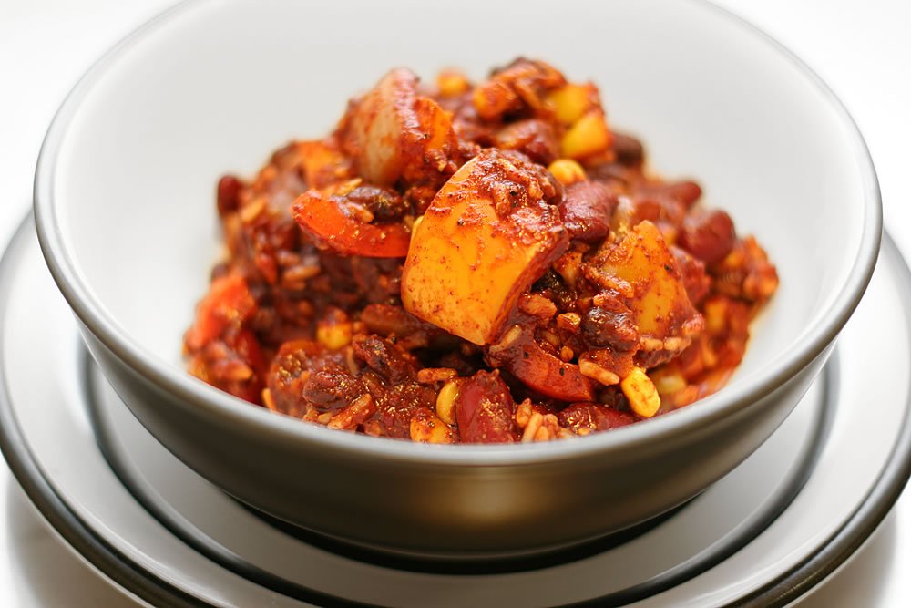 A close-up shot of a bowl filled with rich chili con carne, showcasing chunks of beef, corn, and beans.