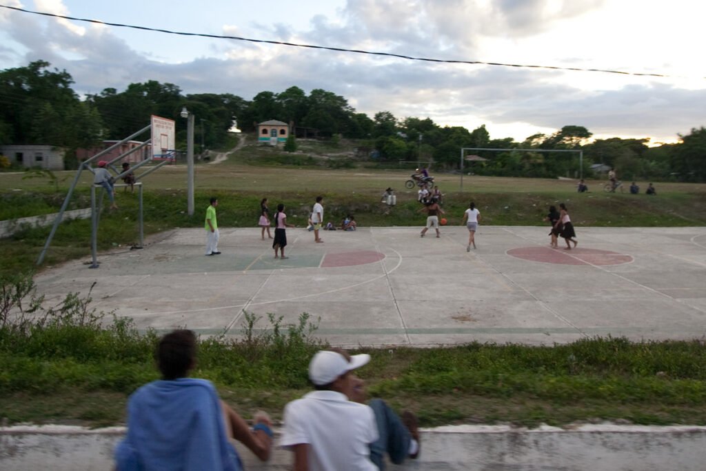 A photo showing spectators watching a basketball game on a local outdoor court.