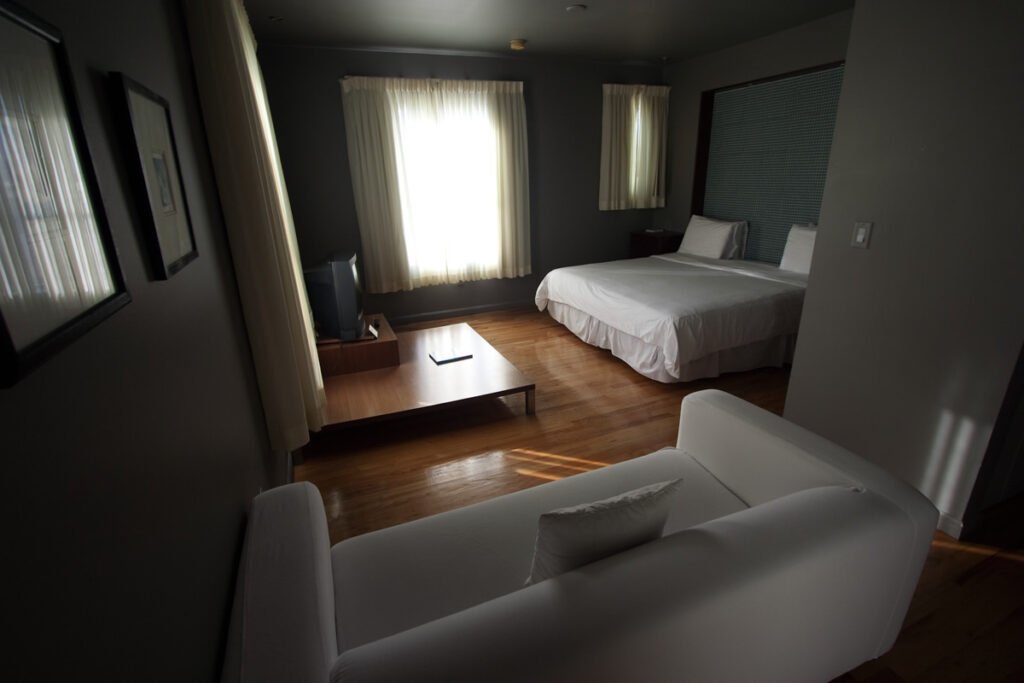 A modern and cozy travel hotel room featuring a neatly made bed and a comfortable seating area with white accents.