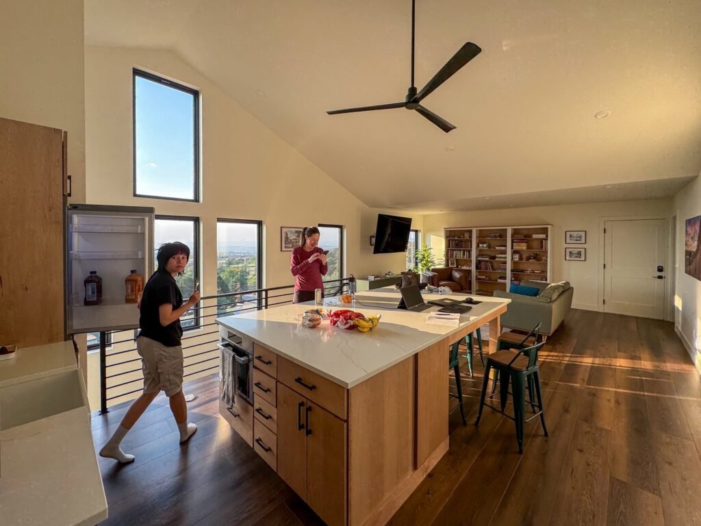 A modern kitchen featuring a large island and a couple walking through the space, enjoying their time together.