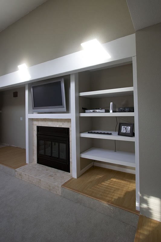 A warm living room corner featuring a fireplace, bookshelf, and soft lighting.