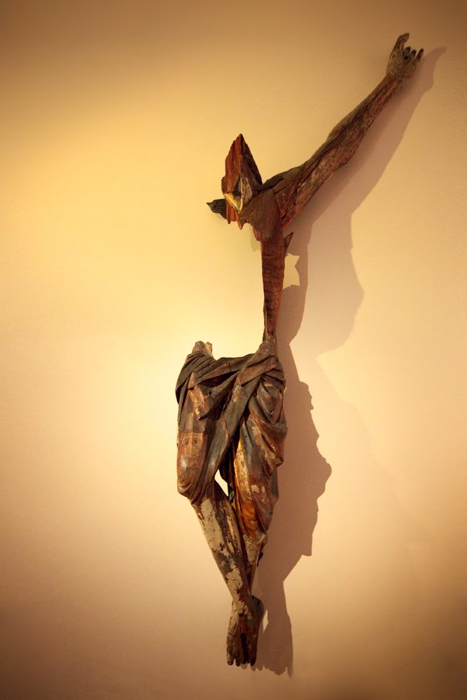 A crucifix casting a shadow on a warm-toned wall.