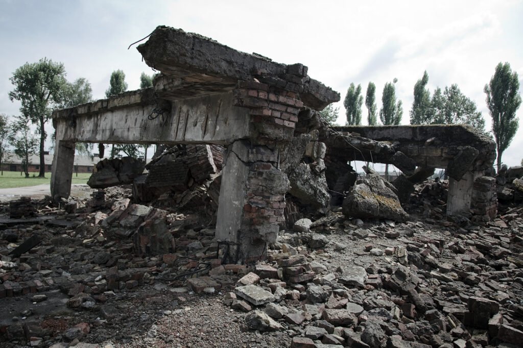 A collapsed bridge amidst rubble with trees in the background.