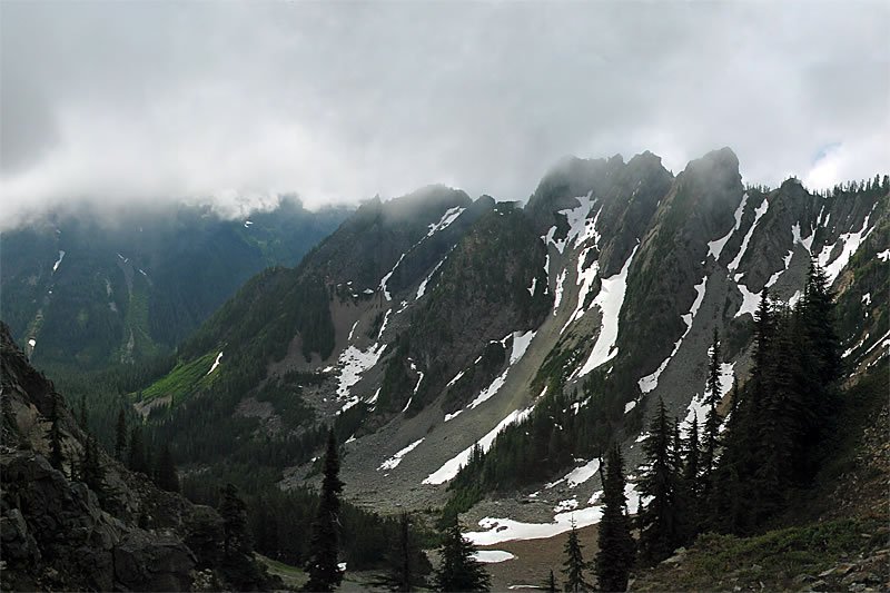 A panoramic view of a rocky desert landscape under a vast sky with scattered clouds.