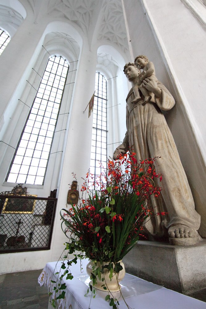 A beautiful church interior featuring statues and vibrant floral arrangements adorning the altar.