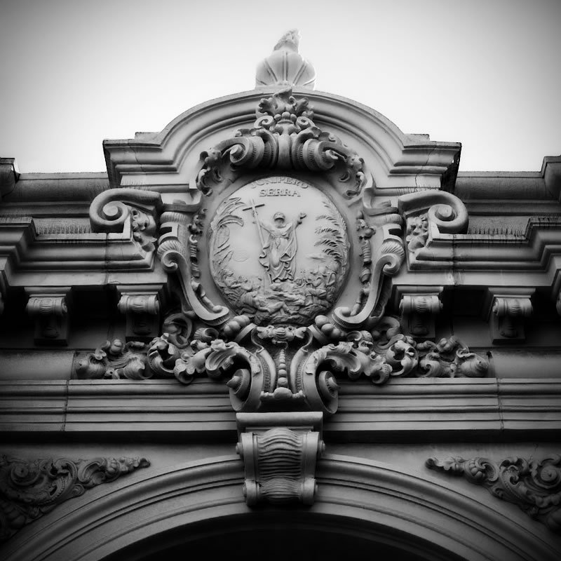 Close-up view of ornate scrollwork and classical architectural elements on a historic building facade, showcasing intricate designs and craftsmanship.