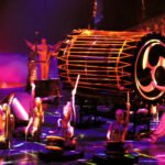 Grand Canyon A vibrant stage performance featuring musicians playing large drums under colorful lighting.