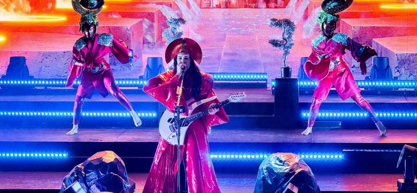 Empire of the Sun at Red Rocks Erykah Badu performs live on a brightly lit stage, accompanied by dancers in unique costumes.