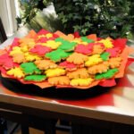 Kristie’s 30th Birthday A tray filled with vibrant, fall-colored leaf-shaped cookies on a dining table.