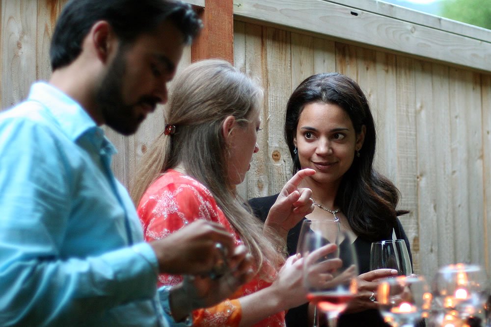 A group of friends sharing a moment over wine in a cozy outdoor setting with a wooden backdrop.