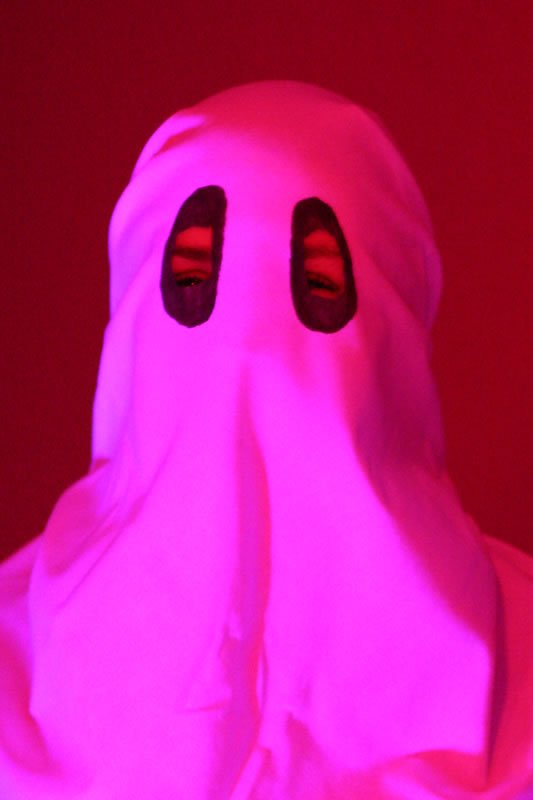 A haunting image of a ghost in flowing white robes, illuminated by eerie pink lighting.
