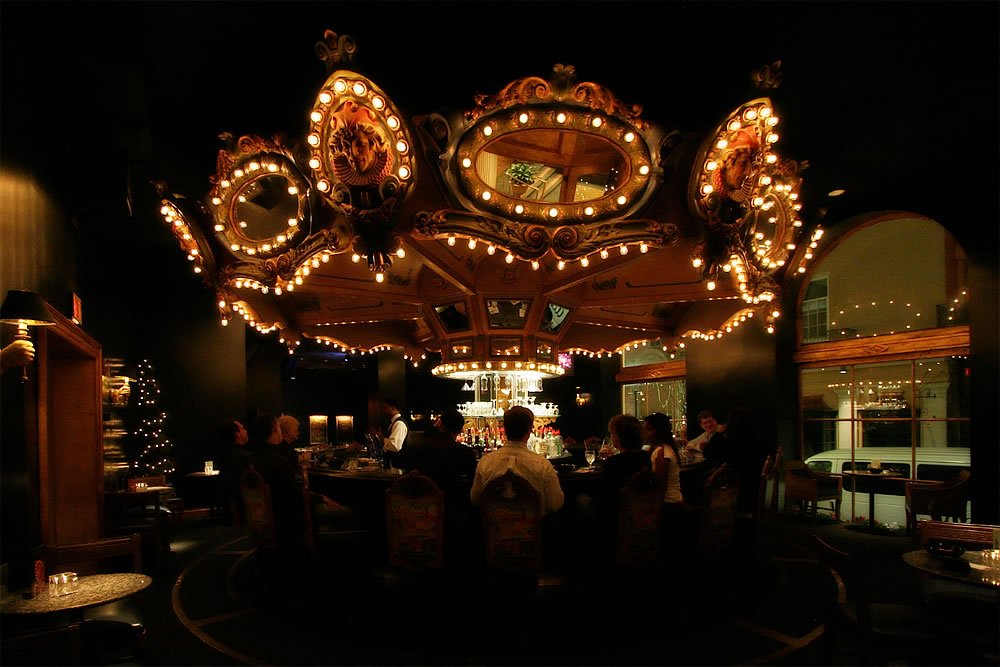 A beautifully lit carousel spins under the night sky, illuminating the festive atmosphere.
