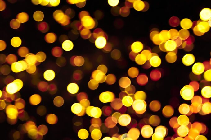 Abstract image showcasing golden bokeh lights against a dark background, creating a magical and festive atmosphere.