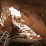 Devil’s Chair A wooden ladder leads into a narrow cave opening carved into reddish-brown rock walls.