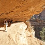 Bryce Canyon Tourists walking along a sandy trail to Mesa Arch in the Utah desert.