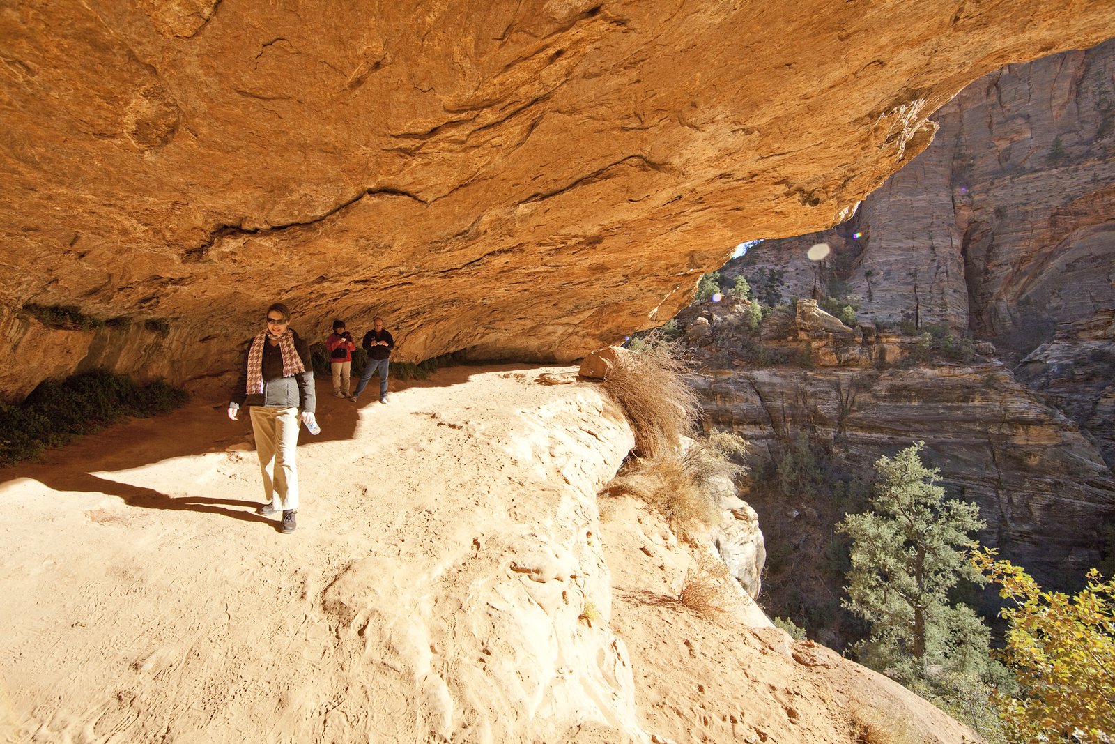 Zion National Park Tourists walking along a sandy trail to Mesa Arch in the Utah desert.