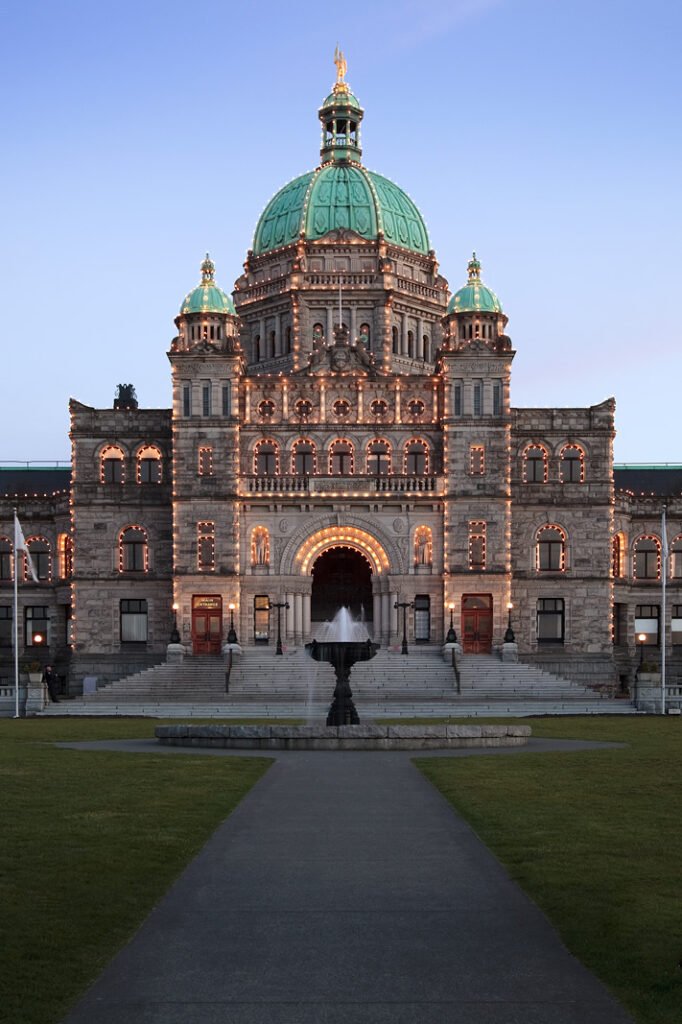 A majestic building with a green dome lit up at dusk, showcasing its ornate architecture against the twilight sky.
