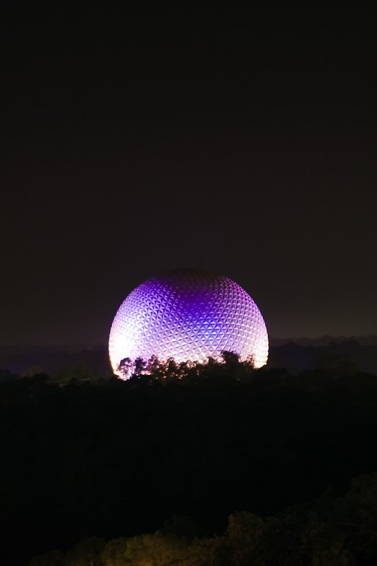 The iconic dome illuminated in purple and white hues against the night sky.
