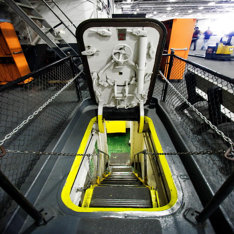 An industrial escalator enclosed by a chain-link fence and safety gates. bright yellow and gray tones dominate the scene.