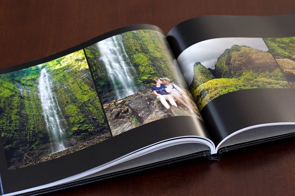 A photo book open to a spread featuring lush Pacific Northwest scenery. One photo highlights Marymere Falls in Washington, complete with a posed couple enjoying the natural surroundings.