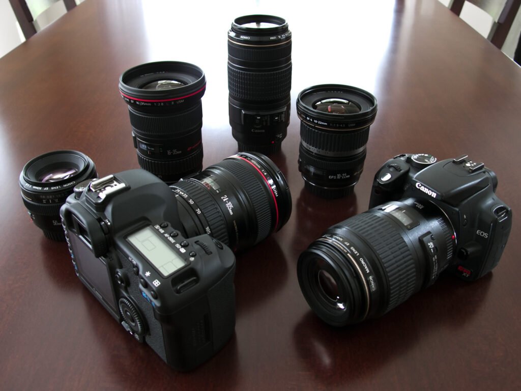 Professional cameras and lenses set on a polished wooden table, highlighting the gear used by John & Kristie for their photo blog.
