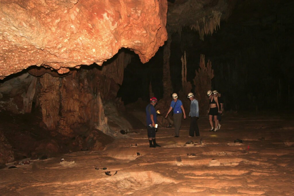 Kristie and John explore a dimly lit cave with rugged rock formations.