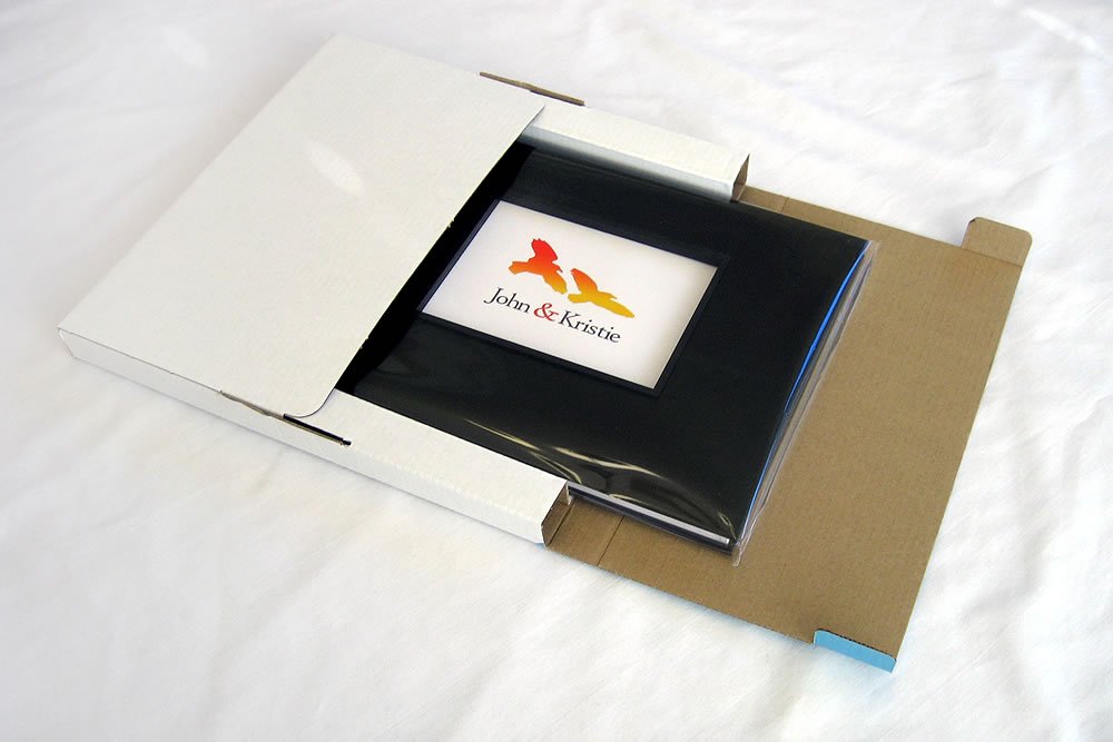 Unboxing a John & Kristie photo book. The book is open inside a simple cardboard box.