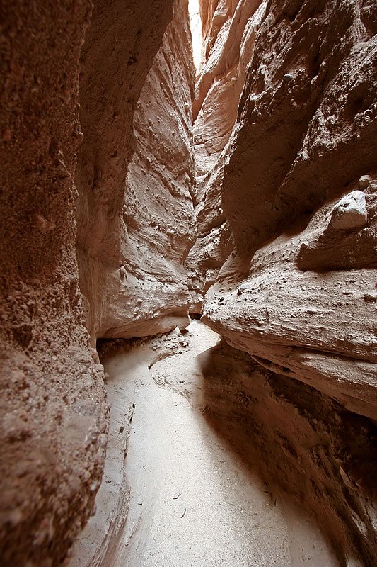 A view of John and Kristie hiking through a narrow and textured canyon passage.