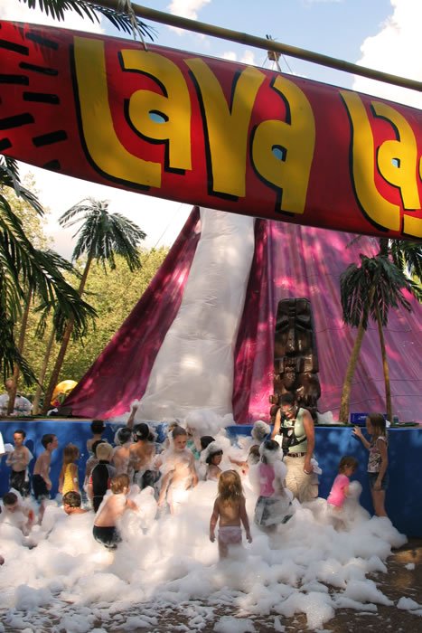 Photos of a vibrant foam party at Lava Land. Children play in foam under a red sign with tropical decor.