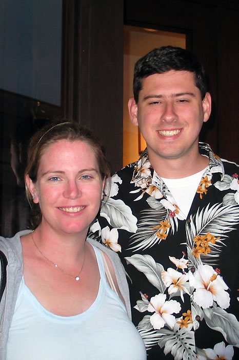 A photo of John and Kristie, smiling warmly. John is wearing a floral shirt, and Kristie has a light necklace.