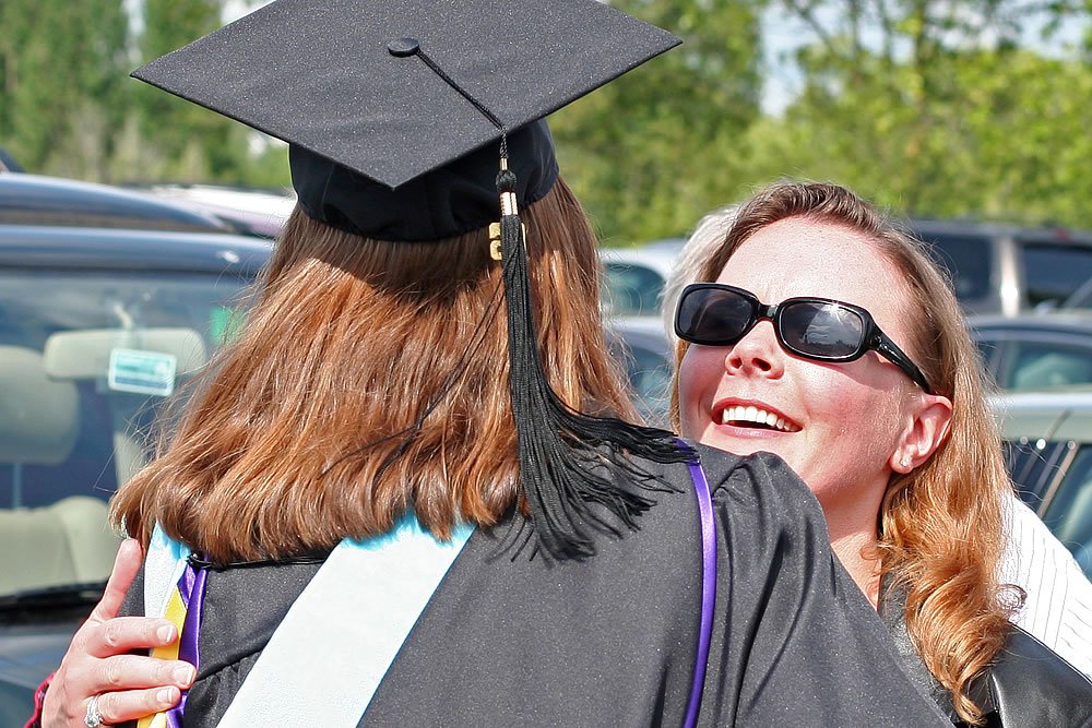 Two women embracing warmly, one in graduation attire, showcasing celebration and happiness.