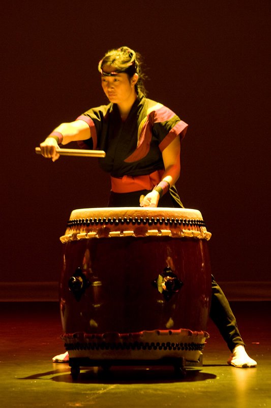 A skilled musician is captured playing a traditional taiko drum at a lively Kokeshi performance. The dynamic pose and intense focus reflect the rich cultural heritage of Japanese drumming.