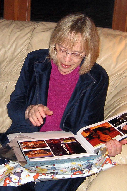 December 24, 2005. Kristie is pleased and surprised to find a gift from John in the form of a photo book she made a few years ago. Photo by K. R. Holland.