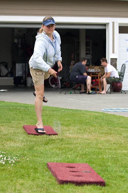 Kristie throws a beanbag in a game of cornhole on the lawn.
