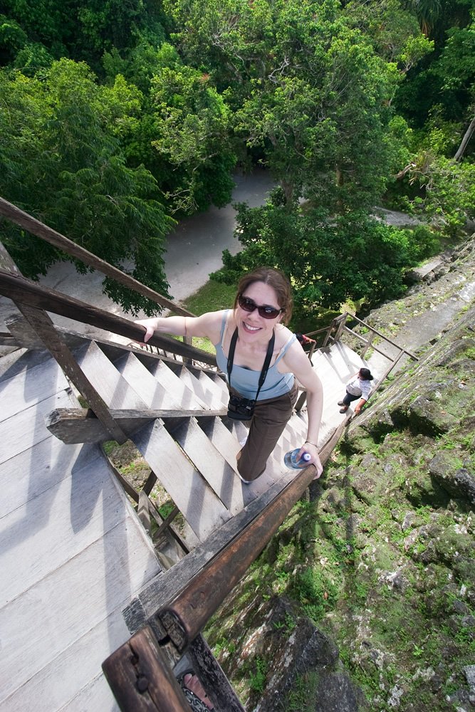 Kristie ascends rustic wooden stairs surrounded by lush greenery during one of our tropical adventures.